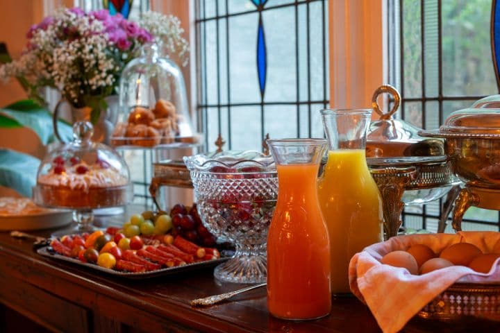 Breakfast of fresh juice, fruit and pastries beside a stained glass window