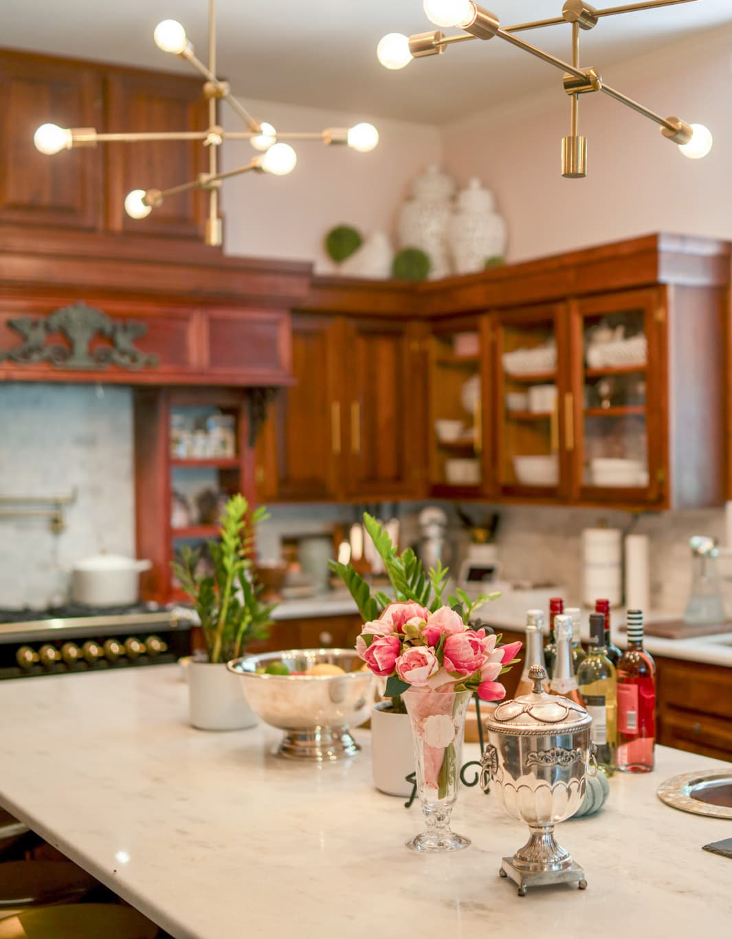 Pink roses and silver serving pieces on the marble island of the inn kitchen