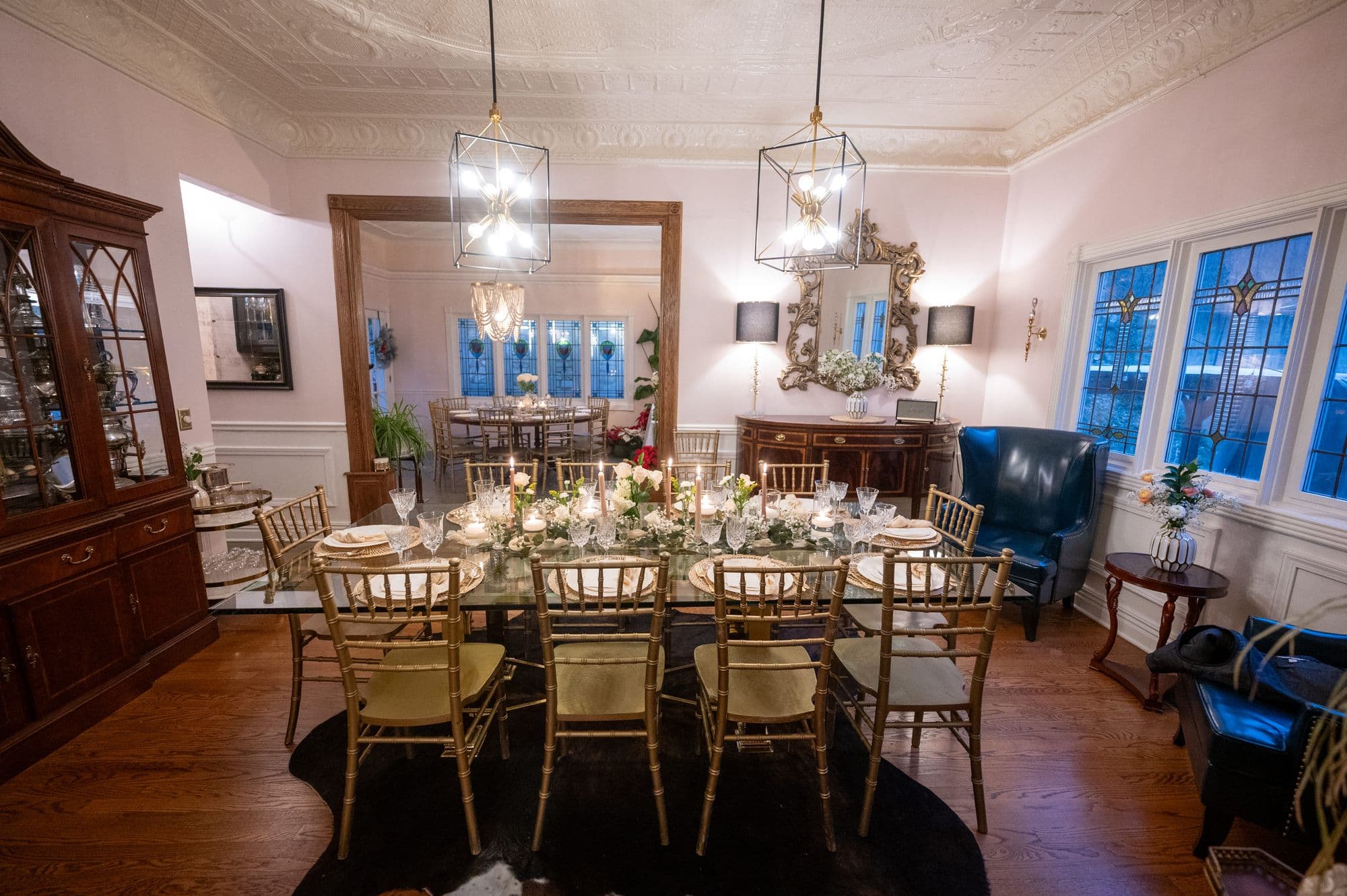 The inn dining room with a glass table, gold chairs and lit candles