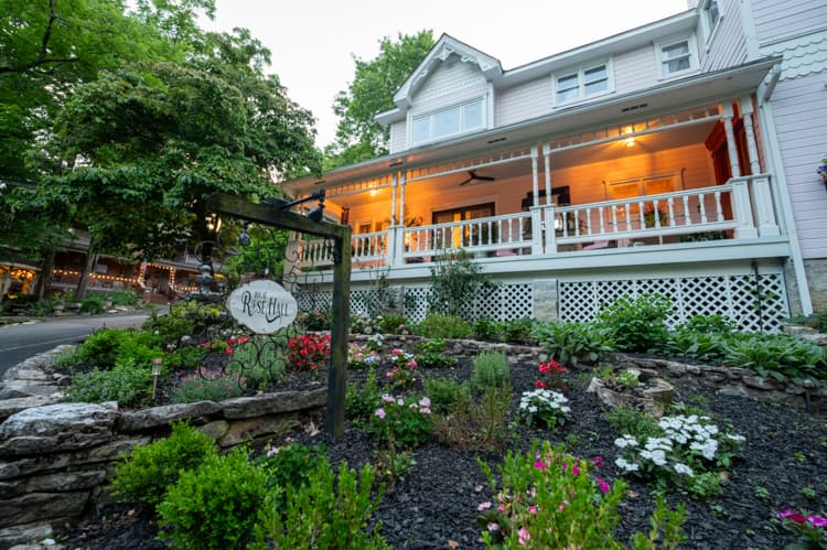 The front porch and garden of Inn at Rose Hall at dusk, with the inn sign beside the path