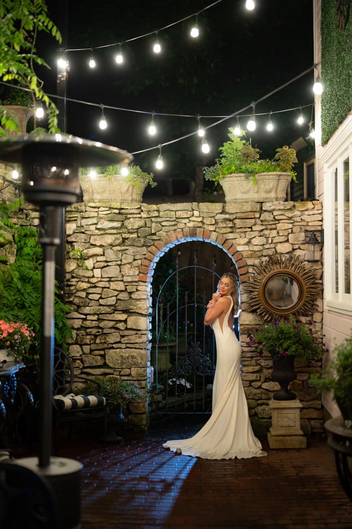A bride beneath the stone archway of the garden courtyard at night
