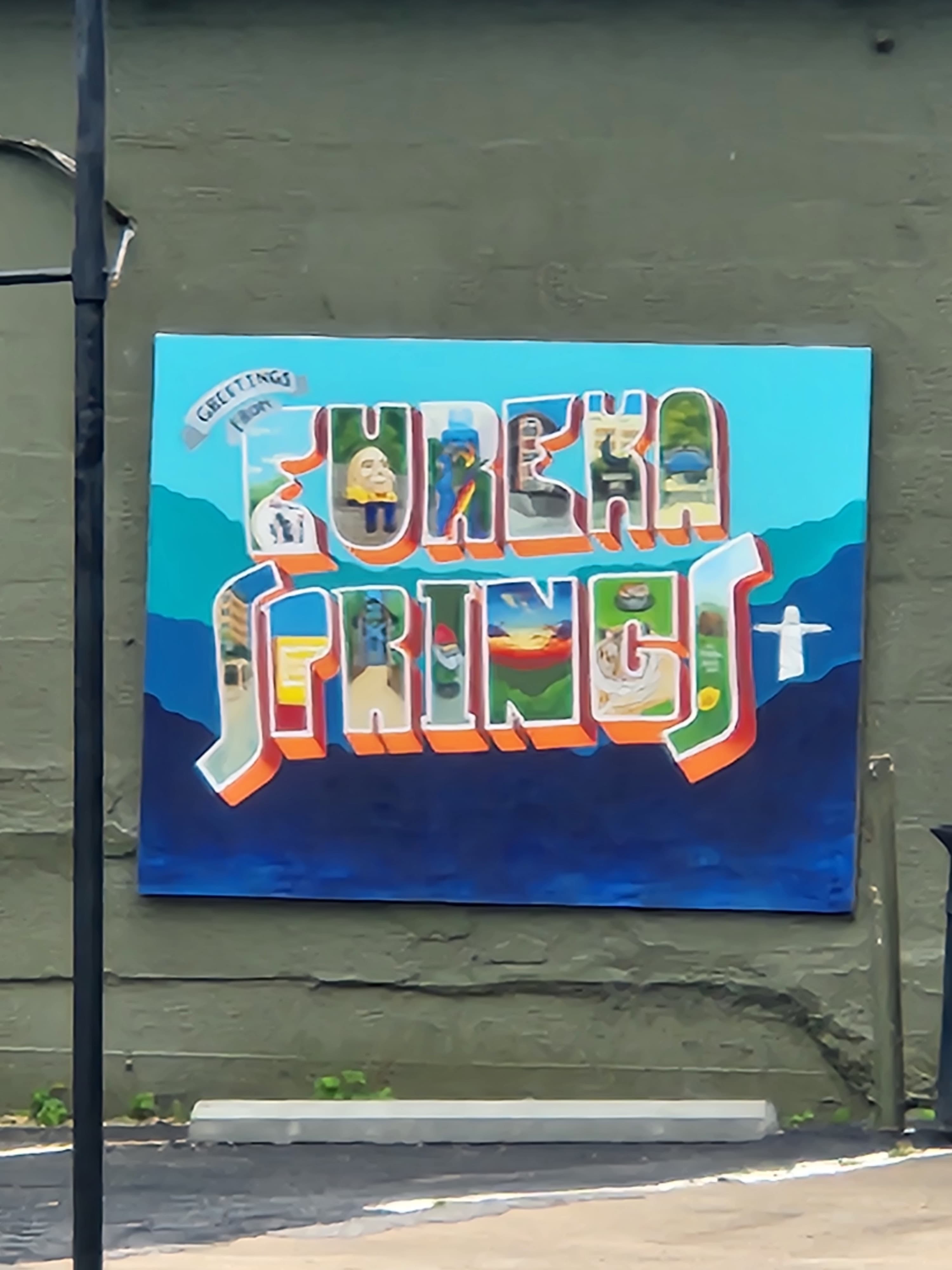 Greetings from Eureka Springs postcard mural painted on a downtown wall